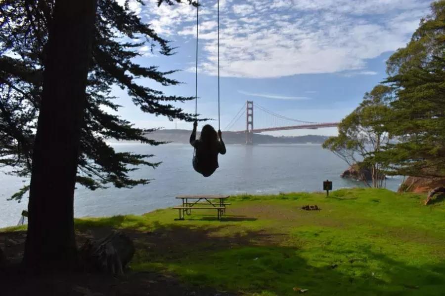 Une femme se balance sur une balançoire surplombant le Golden Gate Bridge. San Francisco, Californie.