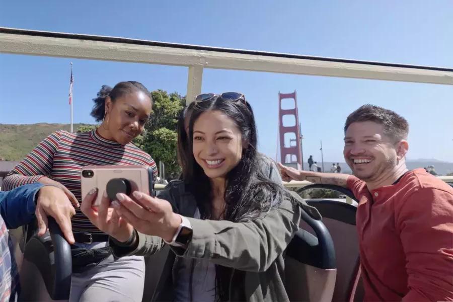 Un gruppo di visitatori si fa un selfie durante un tour in autobus vicino al Golden Gate Bridge. San Francisco, California.