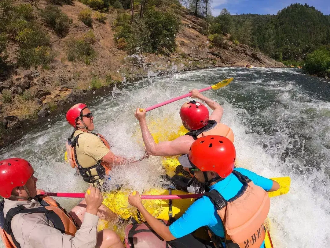 Group of people getting splashed while river rafting on the American River
