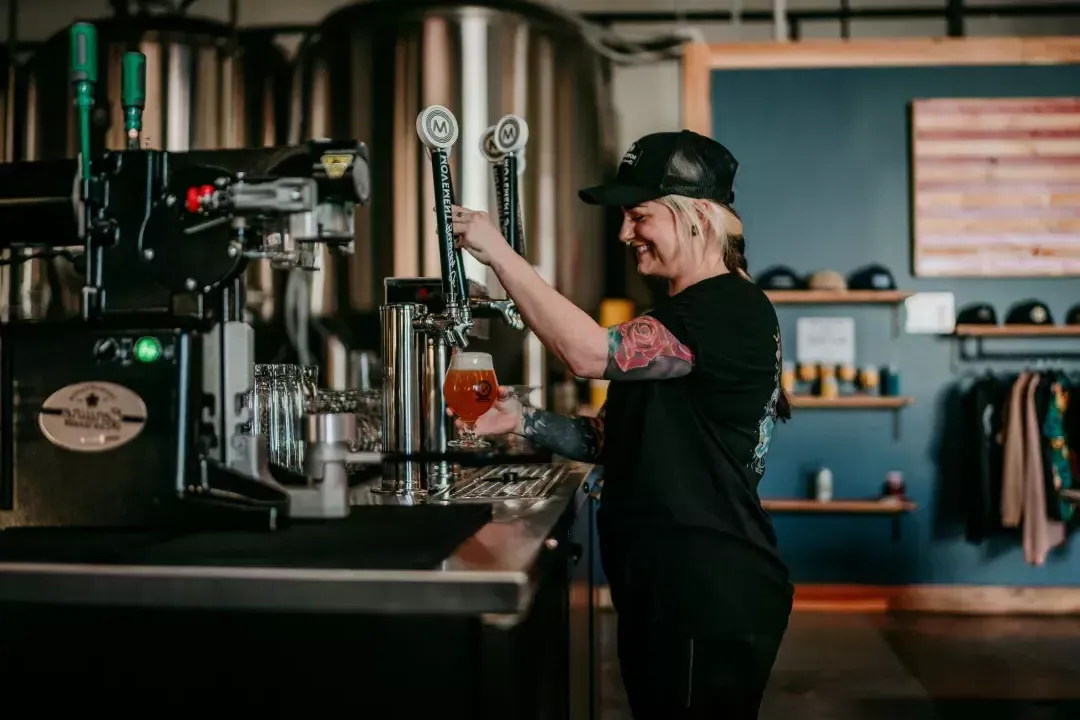 Woman pouring beer into a glass in a brewery