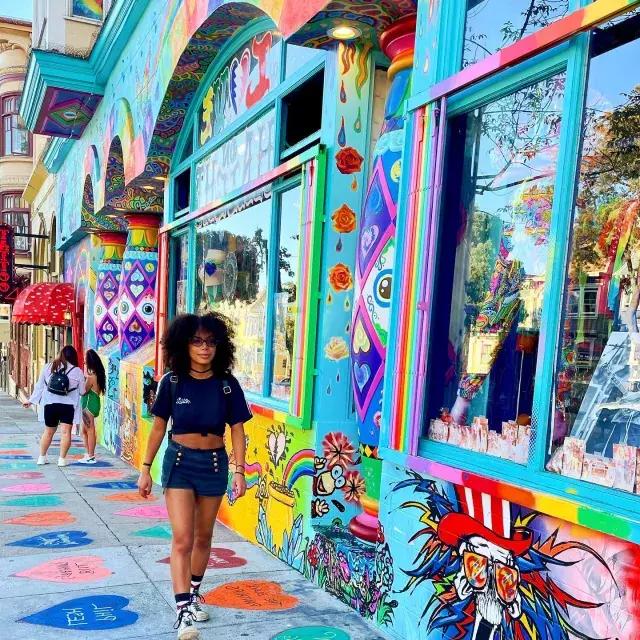 Femme marchant dans Haight Street avec une fresque colorée en arrière-plan.